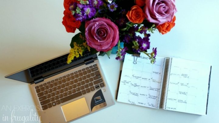 white desk with laptop, flowers and planner
