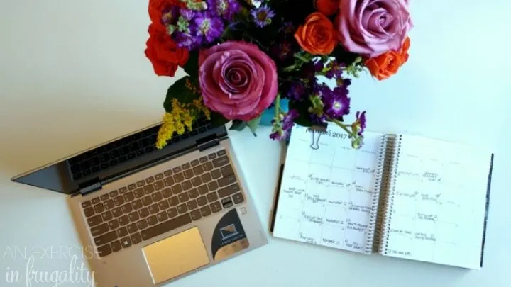 white desk with laptop, flowers and planner