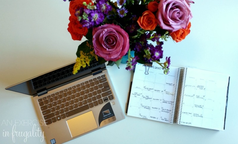 white desk with laptop, flowers and planner