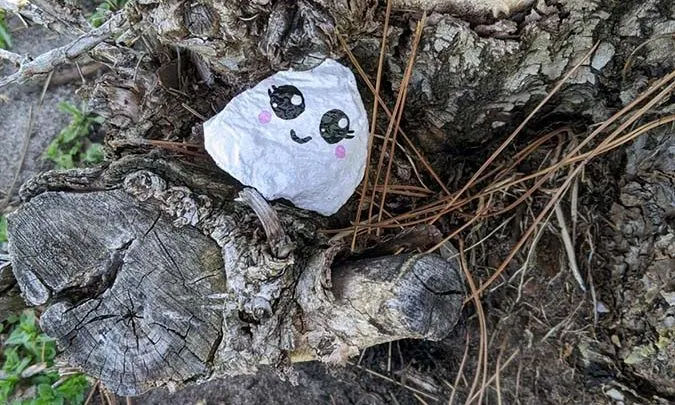 small painted rock with kawaii ghost face on a tree stump