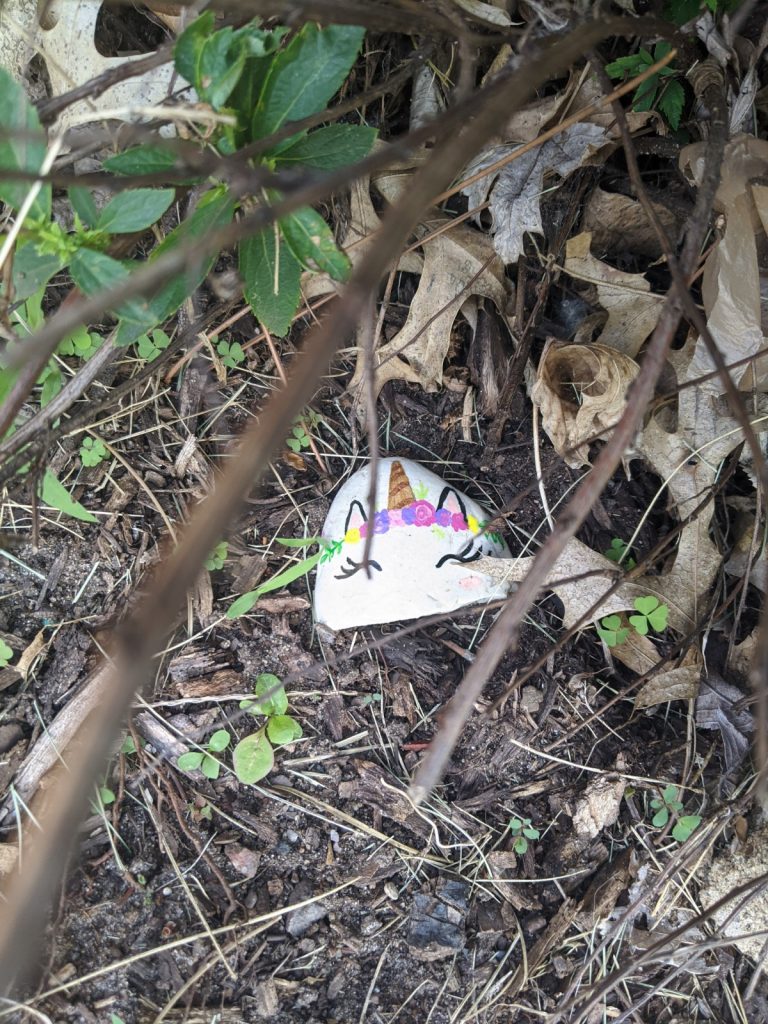 unicorn painted rock hiding in a bush